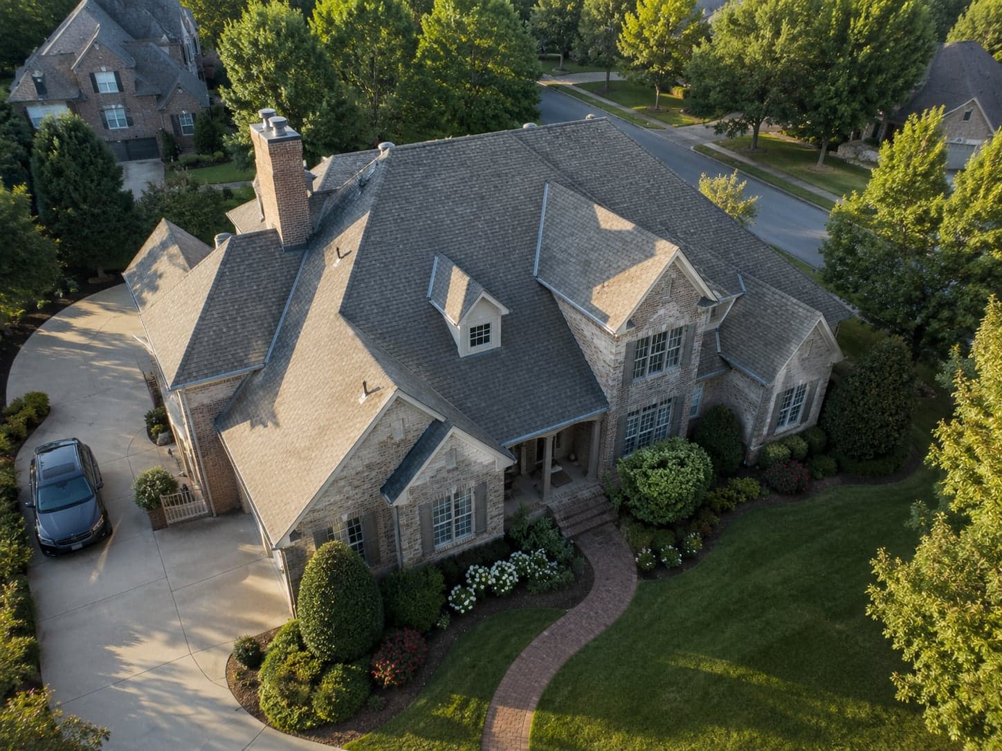 Aerial drone view of a large American home with a complex roofline, captured in daylight